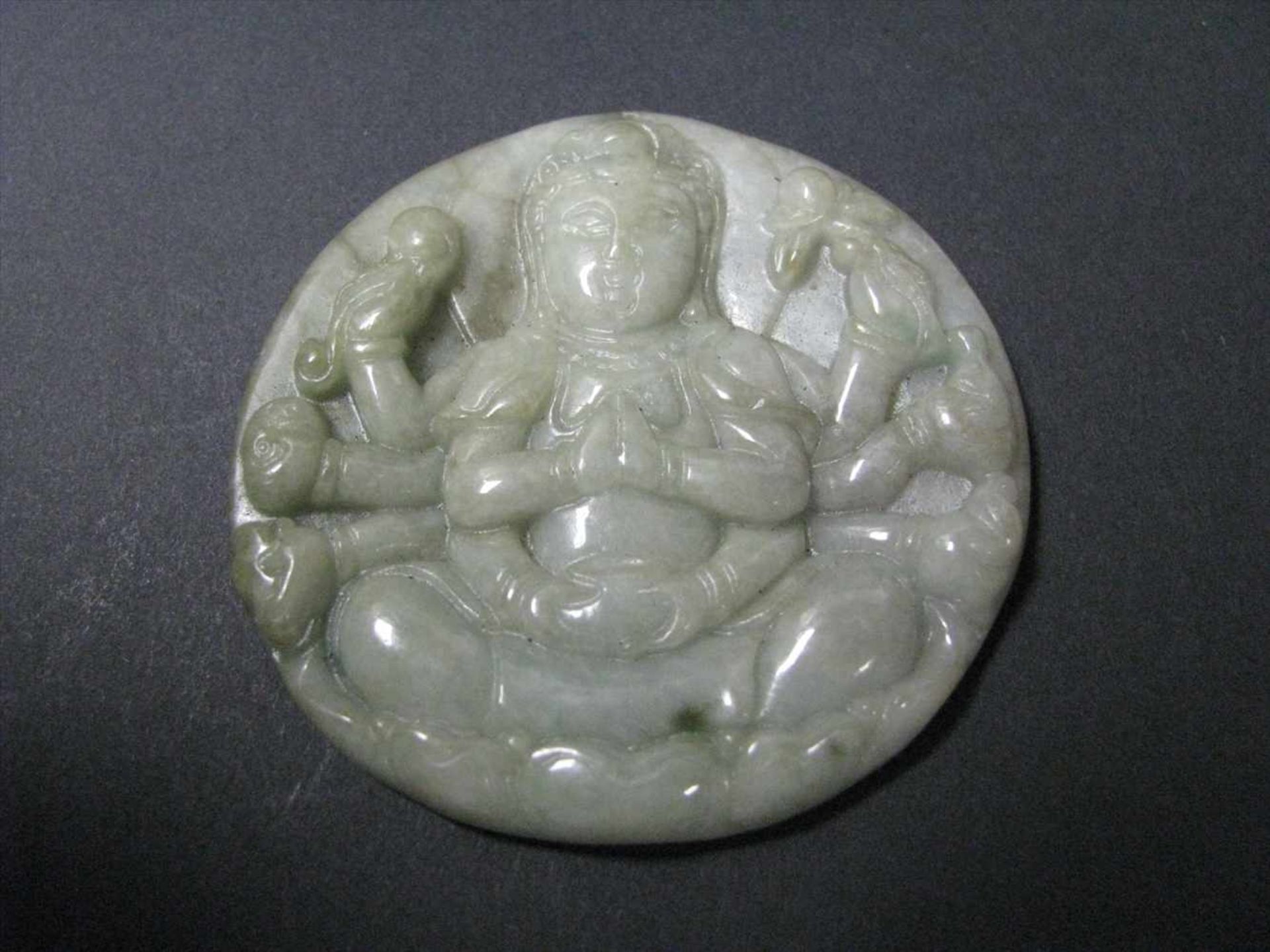 Anhänger, Tibet/Nepal, sitzende, vielarmige Göttin Shiva, weiß-grünliche Jade beschnitzt, d 5,5 cm.