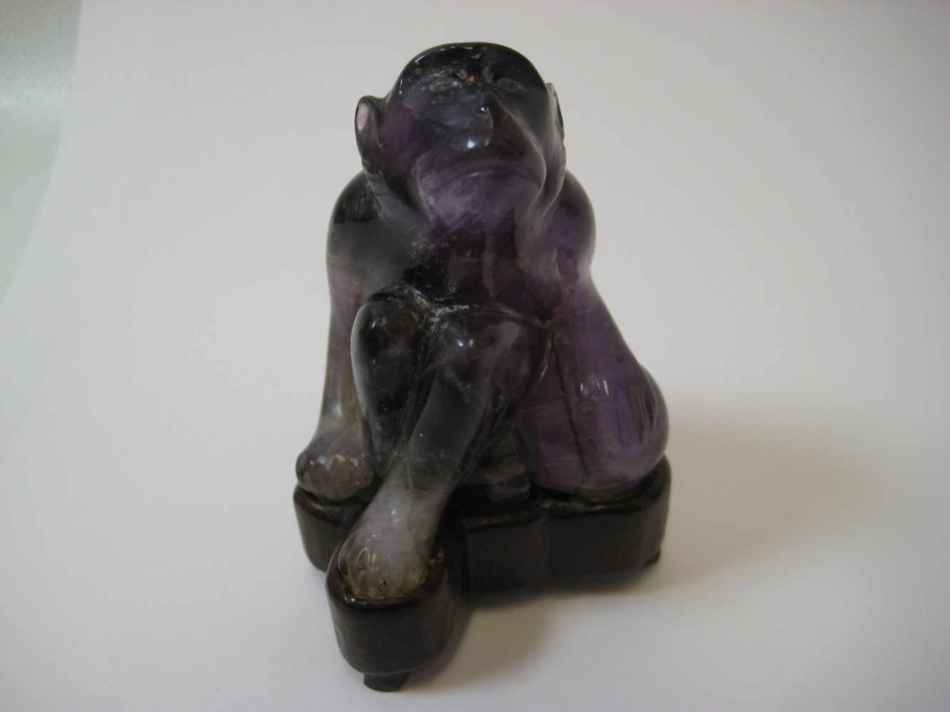 Sitzender Affe, China, Amethyst beschnitzt, Holzsockel, 6,5 x 5 cm.- - -19.00 % buyer's premium on
