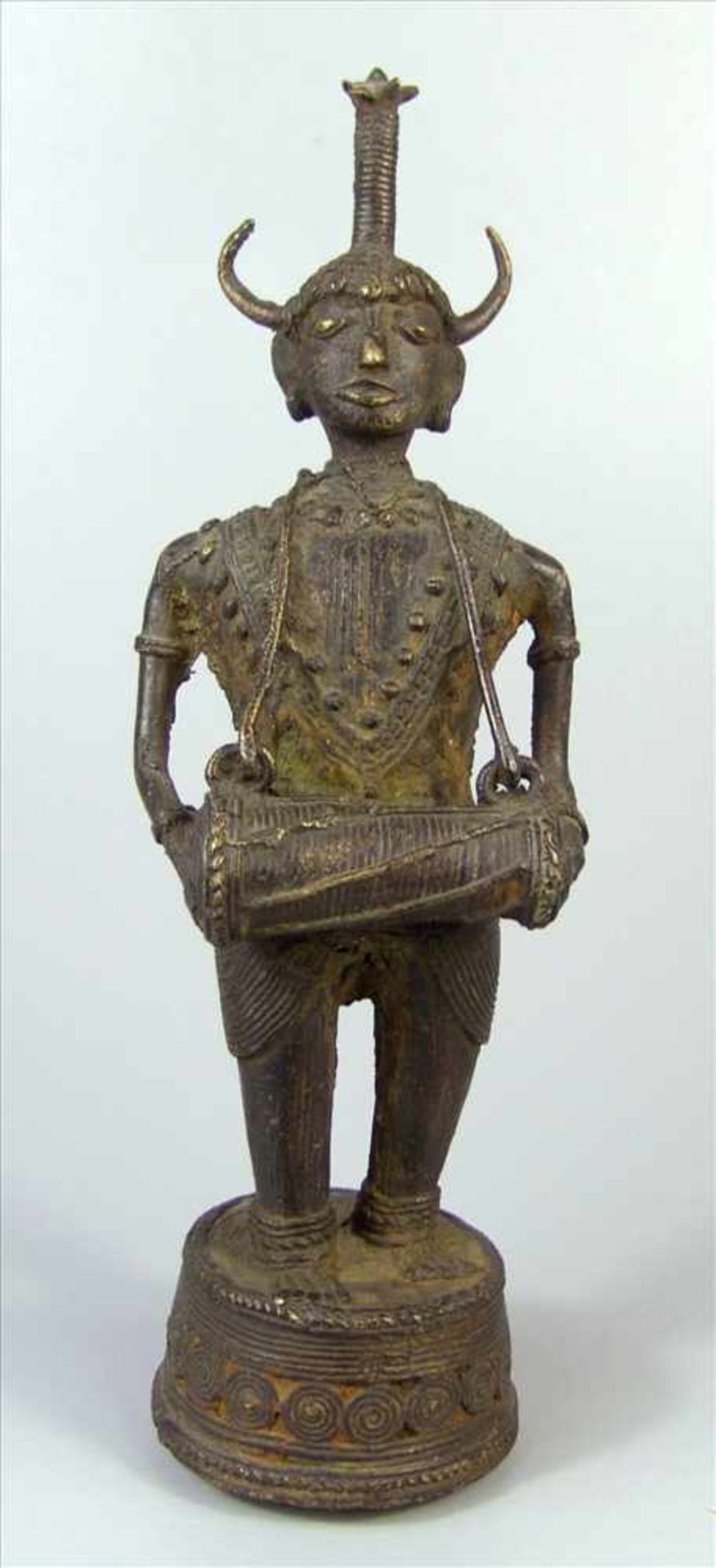 Bastar-Bronze in Form eines Trommlers mit dem Kopf einer Gottheit, Indien um 1900, Gelbguss in
