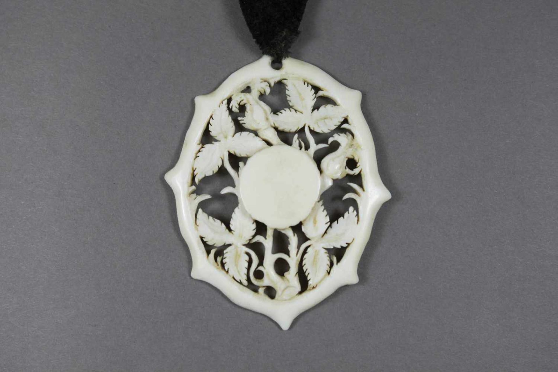 Medaillon, um 1900, Elfenbeinschnitzerei, floraler Dekor mit Durchbrüchen, Maße: 5,5 x 4,5 cm.