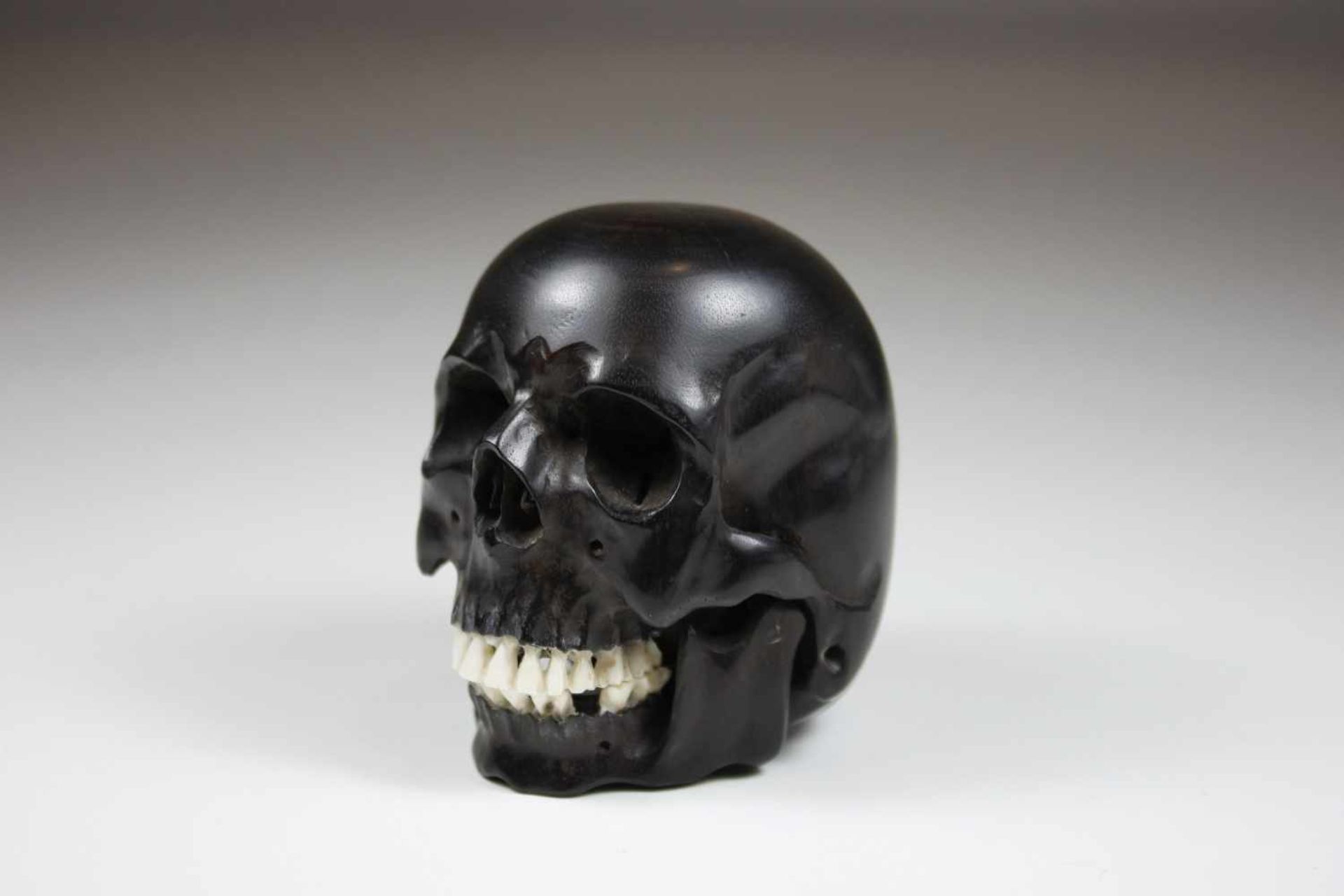 Totenkopf aus Ebenholz, geschnitzt, Holz und Bein, D.: ca. 7 cm.