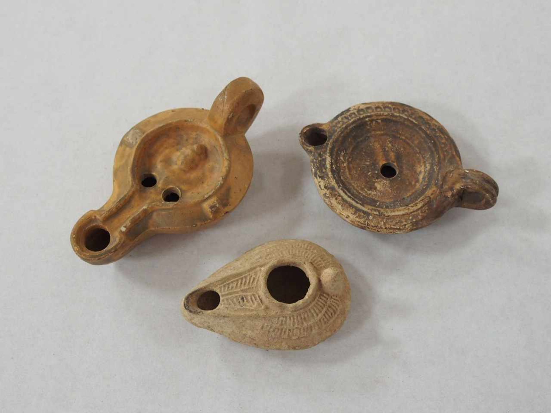 Drei ÖllampenTon, Römisch 1.-5. Jahrhundert n. Chr., Höhe bis zu 5 cm, Länge bis zu 12 cm- - -25.