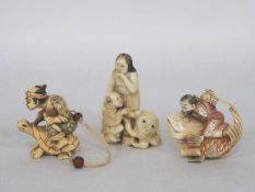 Drei Netsuke in Form von "Menschen und Tieren"Elfenbein, geschnitzt, schwarz unterlegte Gravuren,