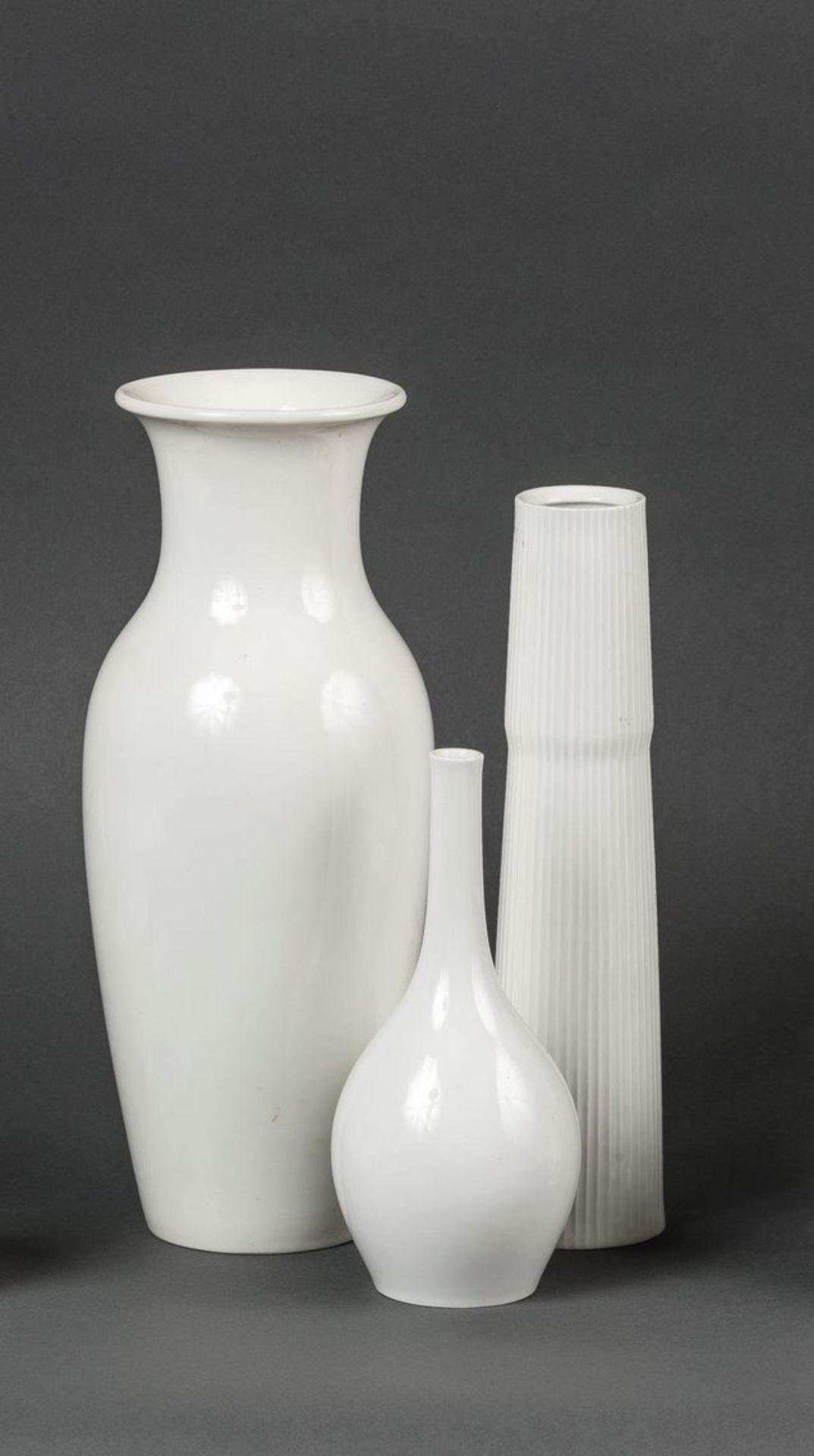 Drei VasenWeißporzellan. Eine große Balustervase mit glatter Wandung, eine Stangenvase mit gerippter
