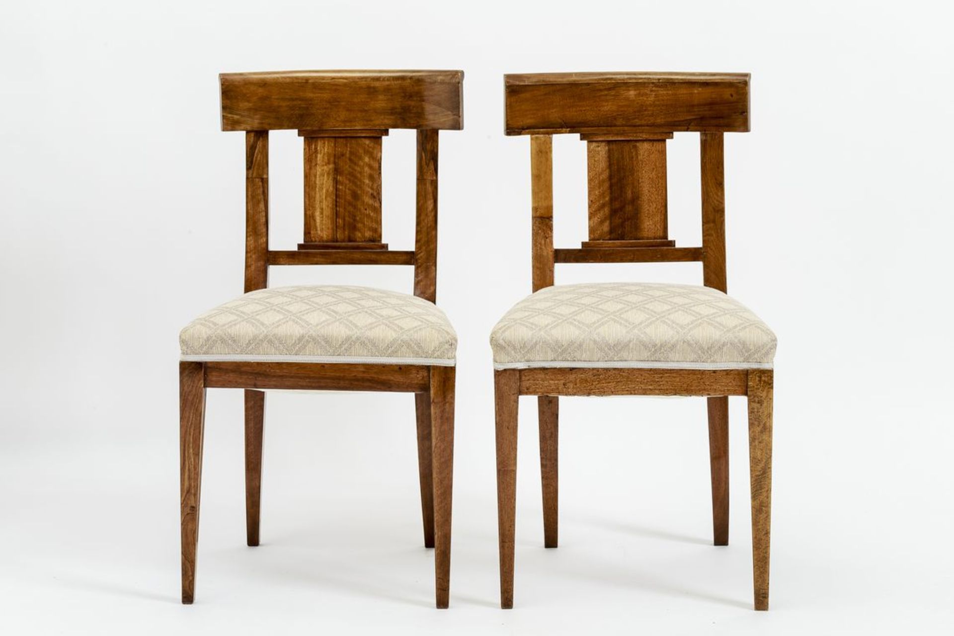 Paar Biedermeier-StühleNussbaum, auf konischen Beinen, trapezförmige, gepolsterte Sitzfläche.