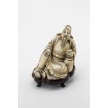 OkimonoElfenbein, fein geschnitten. Darstellung eines sitzenden Chinesen mit langem Bart. In