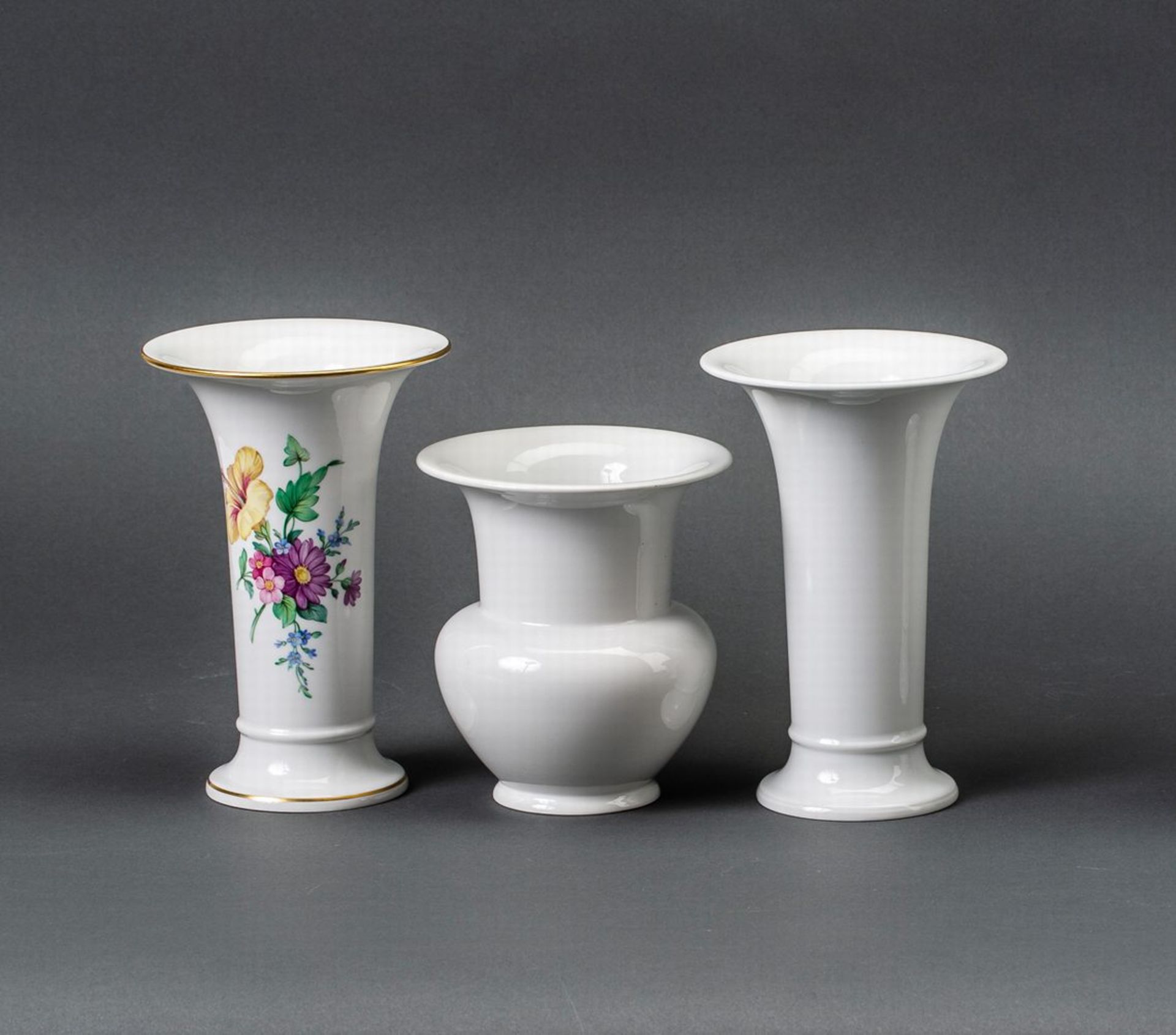 Drei VasenWeißporzellan. Bestehend aus zwei Vasen mit trompetenförmigem Korpus, davon eine mit