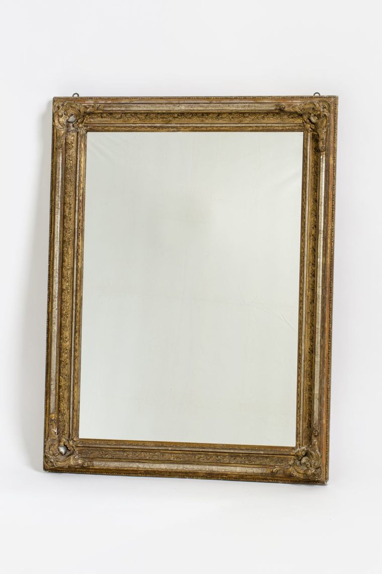 WandspiegelReliefierter Rahmen, ölvergoldet (kl. Fehlstellen). 19. Jh. H. 105 cm, B. 85 cm.