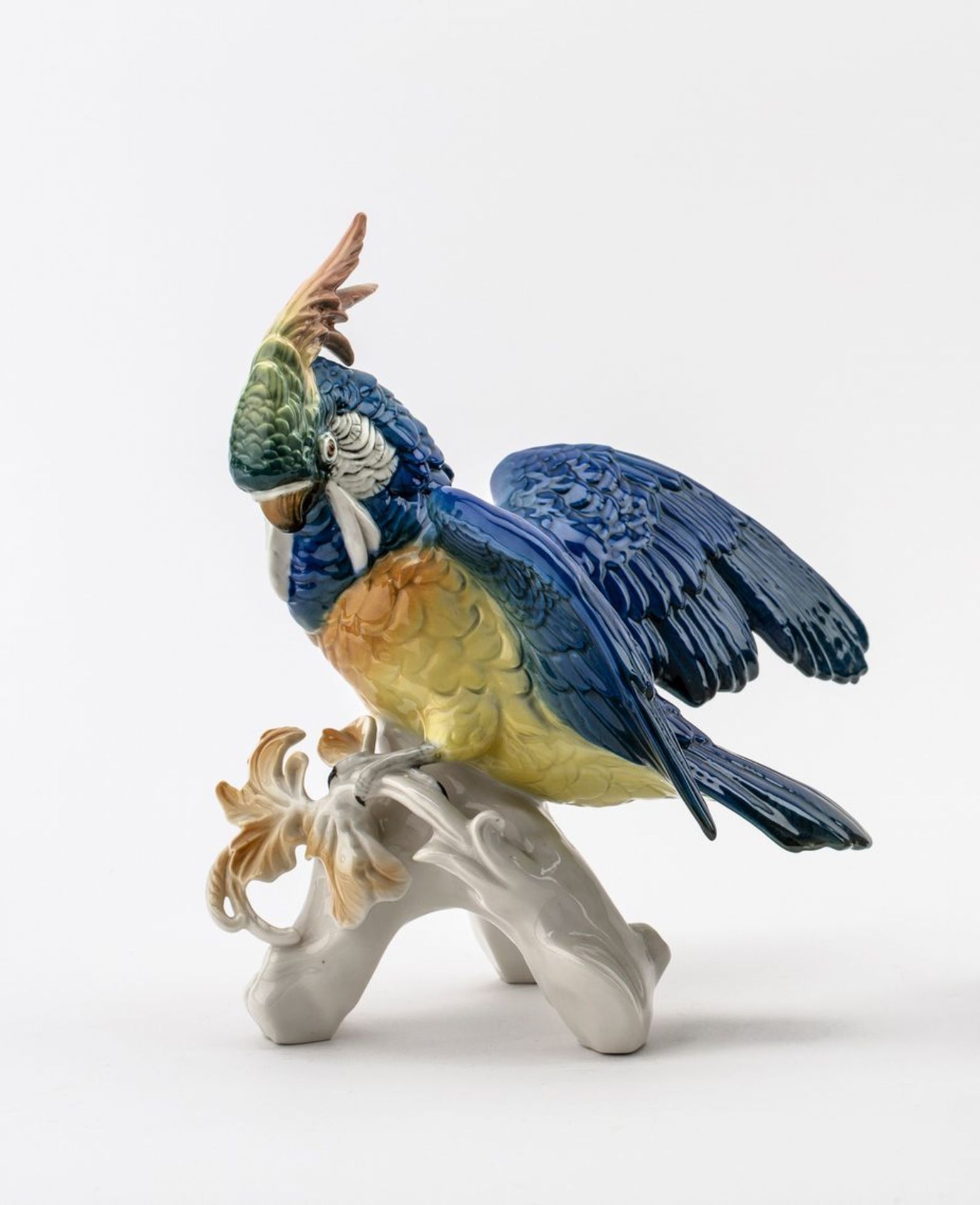 KakaduAuf stilisiertem astförmigem Sockel. Sitzender, seine Flügel ausbreitender Kakadu. Polychrom