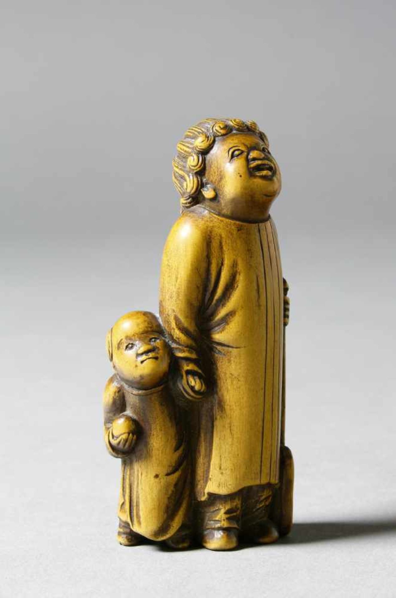 Japan, Netsuke, helles Holz, 19. Jh. Stehender Europäer mit Kind und Spaten. H.: 7,8 cm.