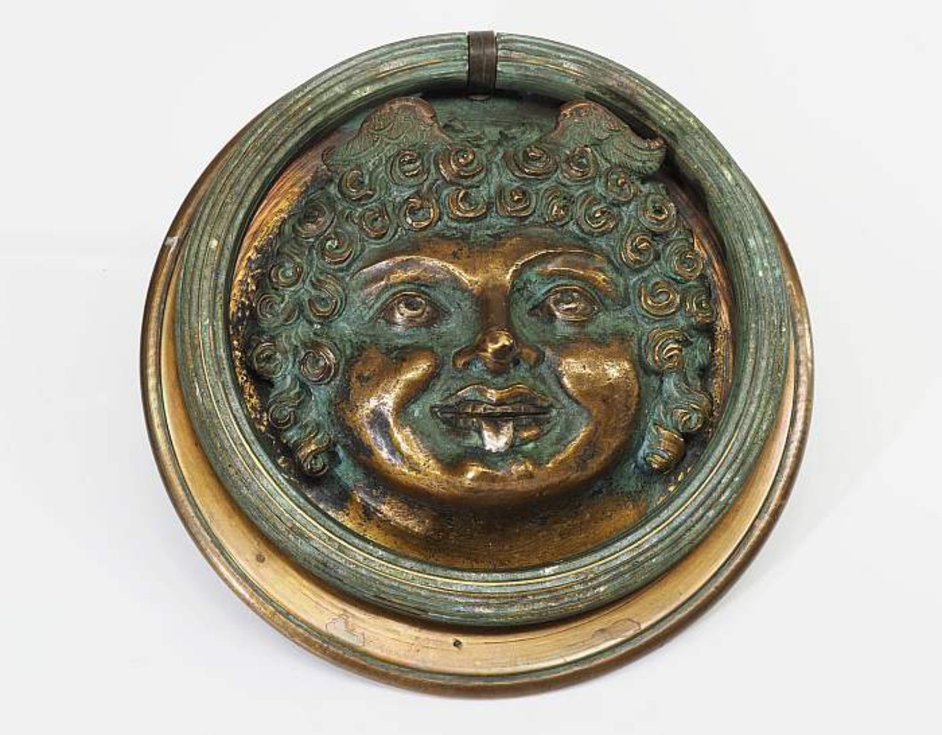 Türklopfer, "Schelm mit herausgestreckter Zunge". Türklopfer, Bronze mit grünlicher Patina, Runder