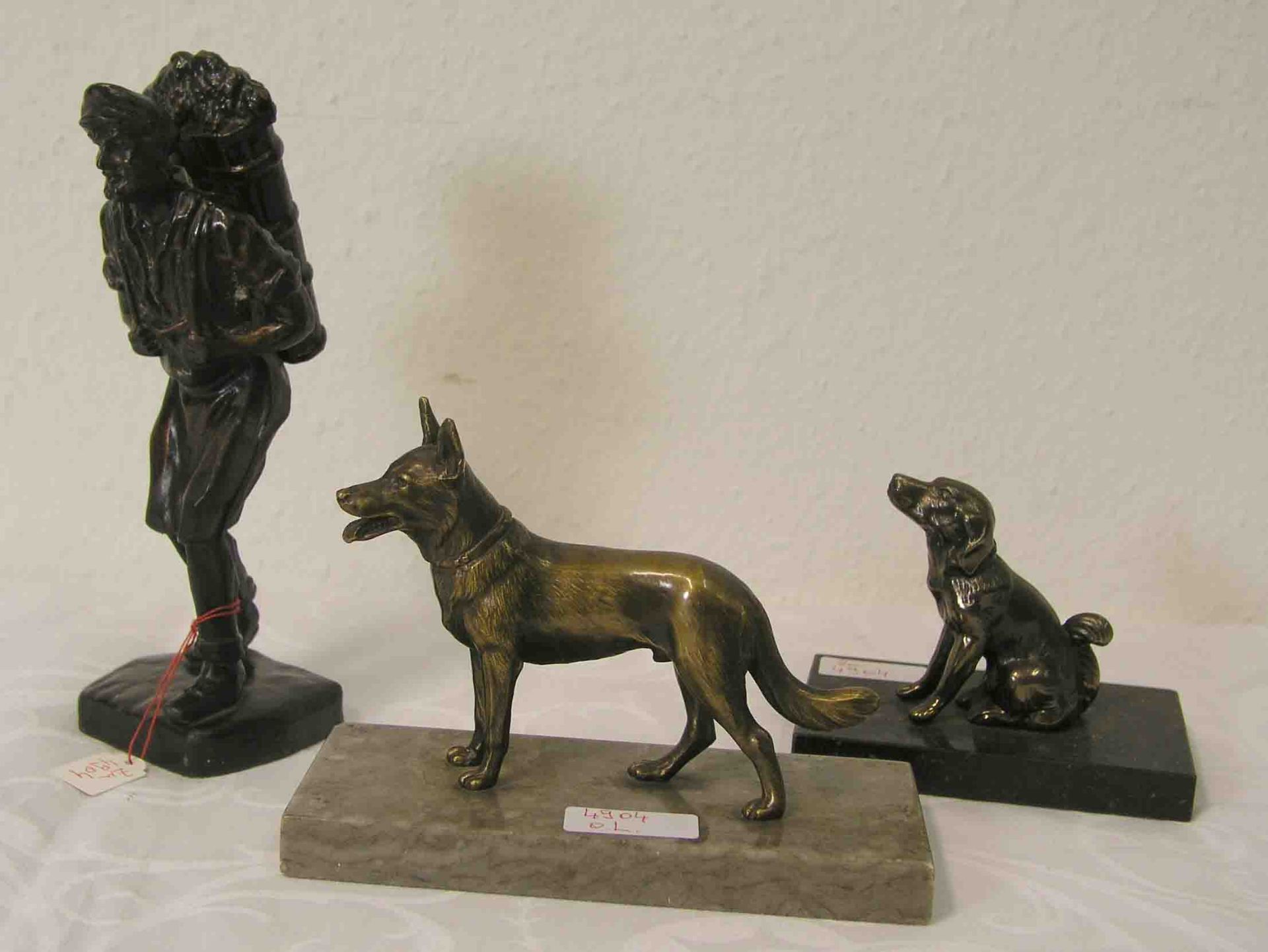 Bauer mit Rückentrage. Höhe: 21cm. Dazu: zwei Hundefiguren auf Marmorsockel montiert,Metallgüsse.