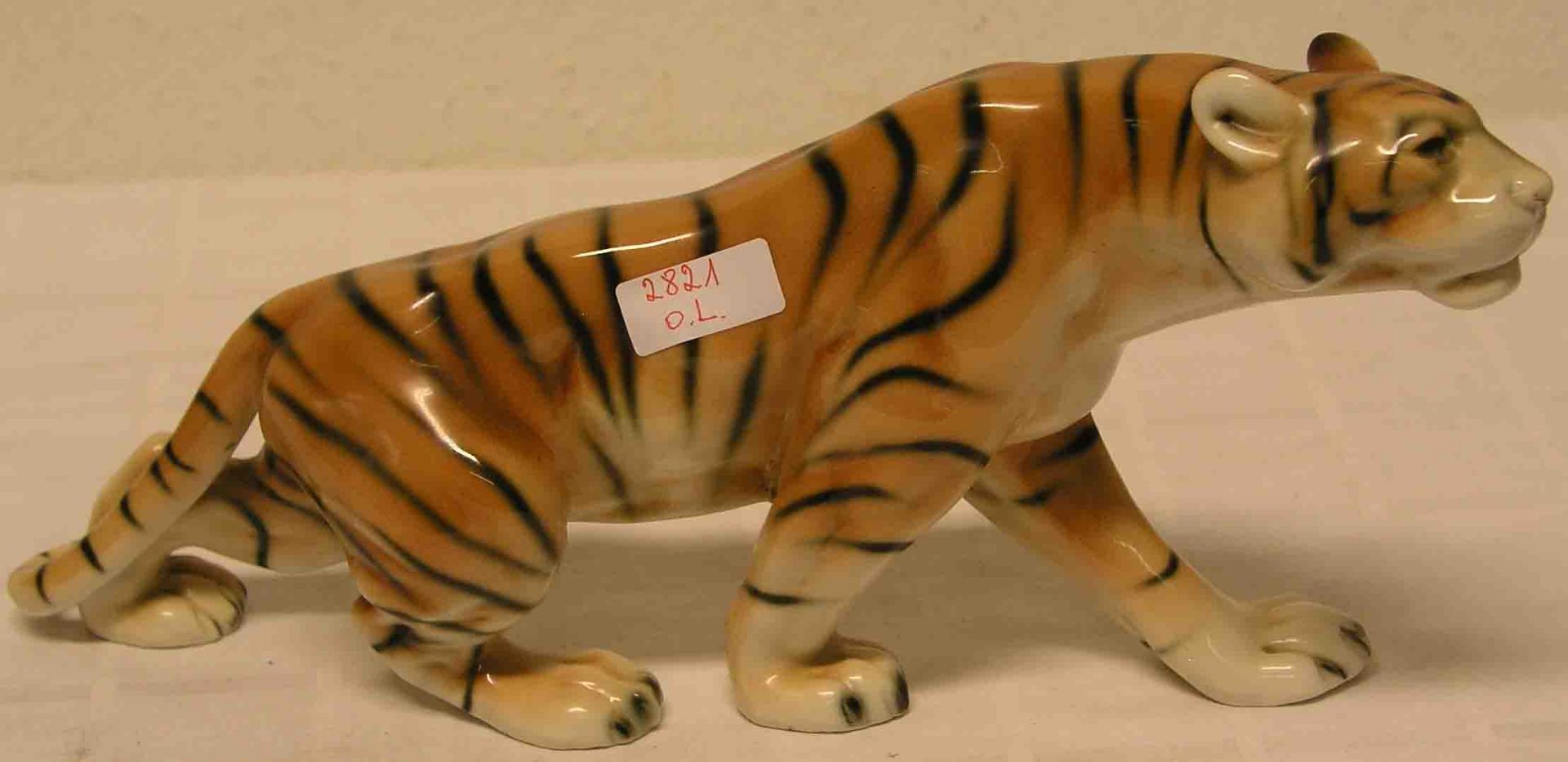 Schreitender Tiger. Porzellan, Royal Dux. Farbig staffiert. Höhe: 16cm, Länge: 34cm.