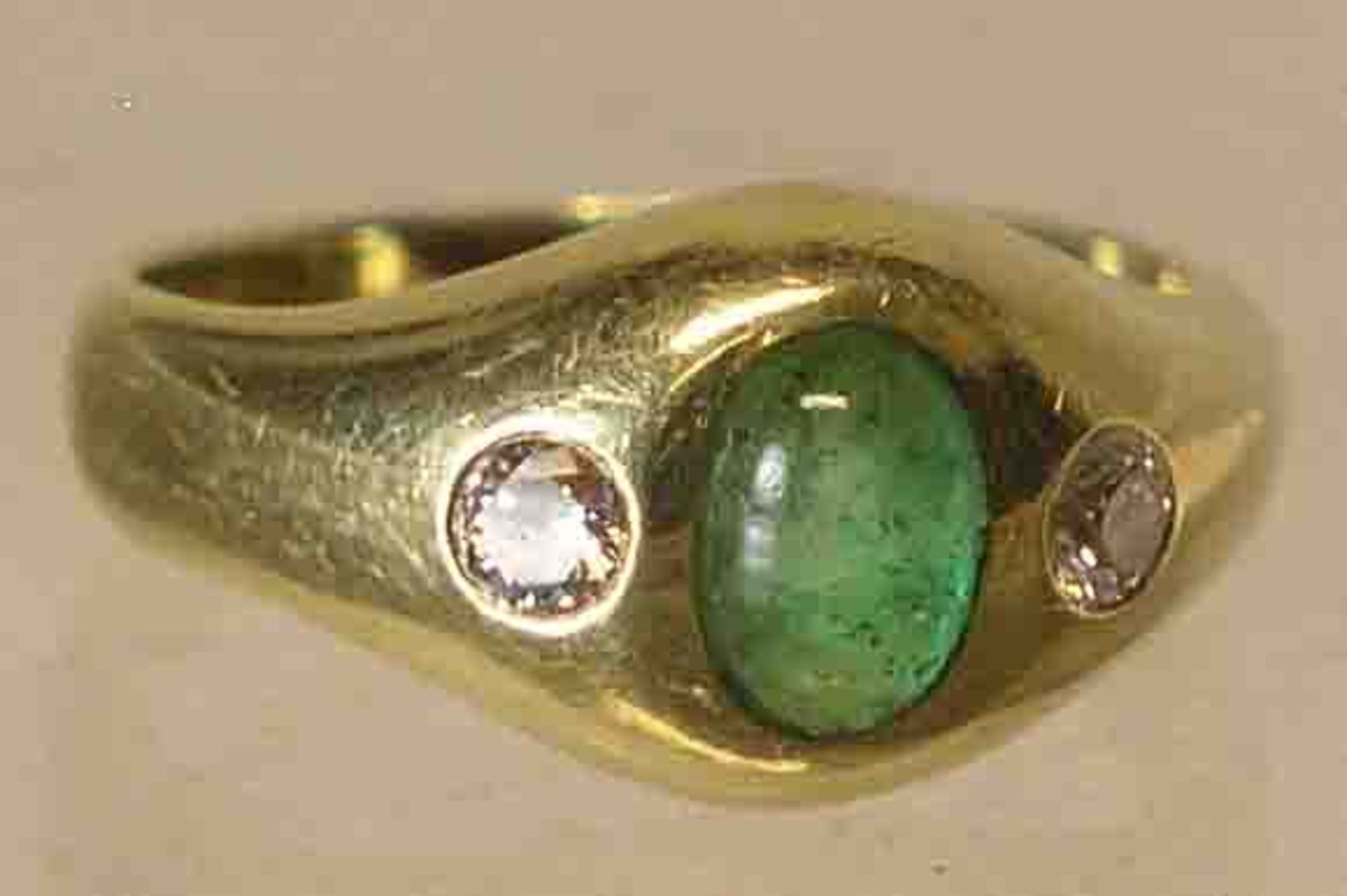 Damenring. 14 kt. Gold. Ringkopf mit zentralem Smaragd (?) Cabochon, flankiert von jeeinem