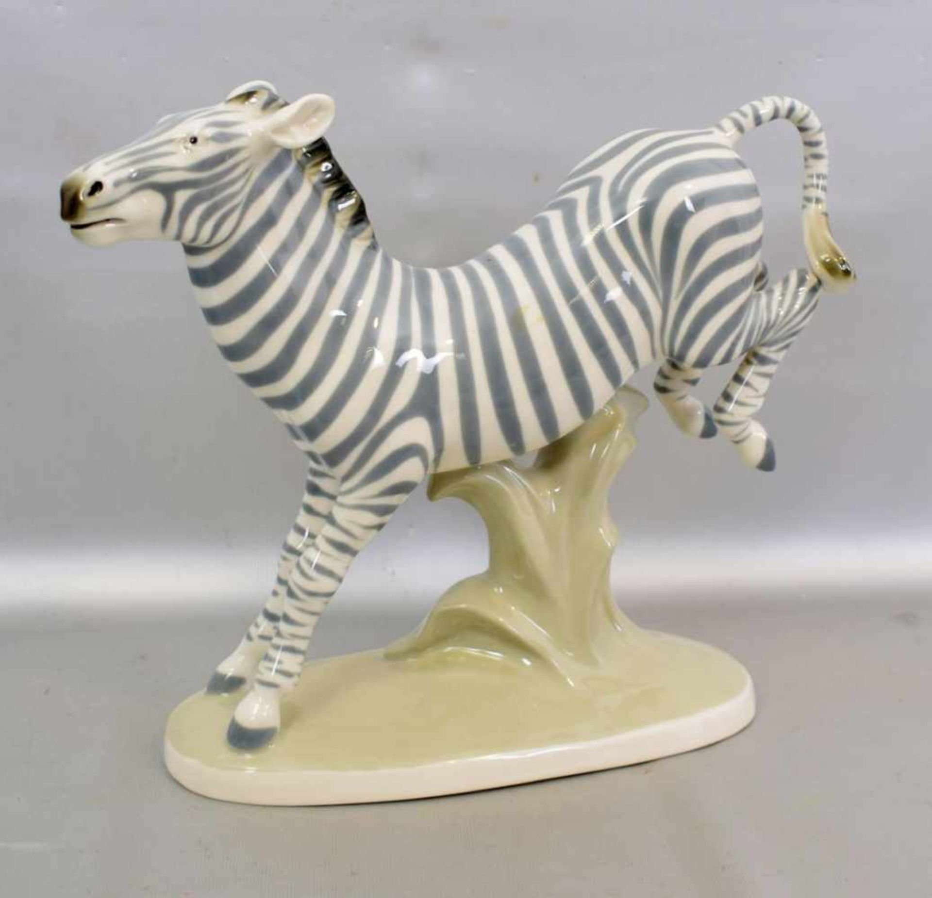 Springendes Zebraauf ovalem Sockel stehend, bunt bemalt, H 26 cm, L 30 cm, FM Dux