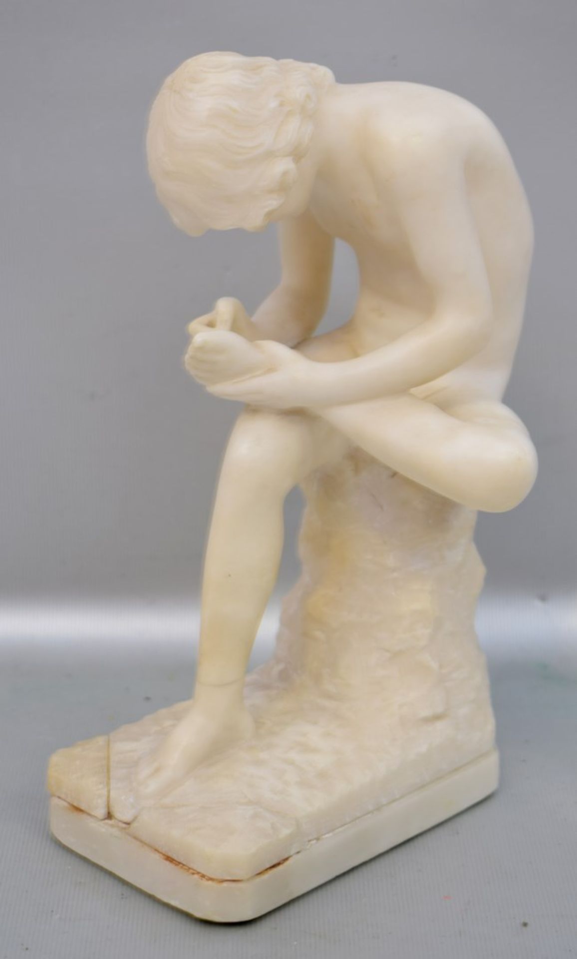 Der DornenzieherAlabaster, auf rechteckigem Sockel sitzend, Sockel rest., H 22 cm, B 13 cm, um 1900