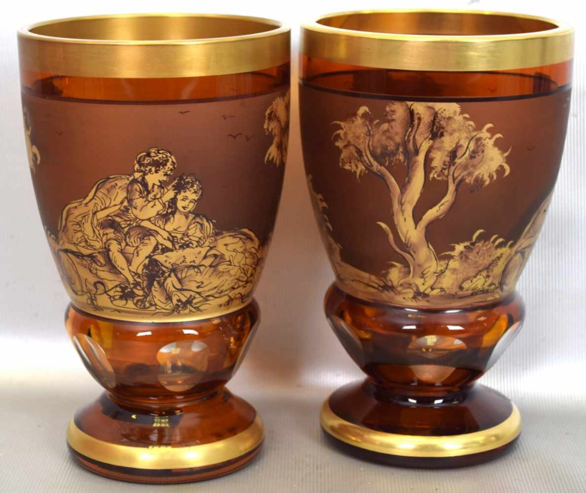 Zwei Becherbernsteinfarbenes Glas, Goldrand, Wandung mit goldenen Watteauszenen verziert, im