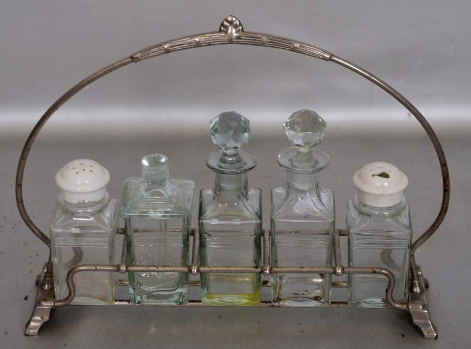 MenageMetallhalterung, mit fünf farbl. Glasgefäßen, verzierter Griff, H 19 cm, B 25 cm, um 1900