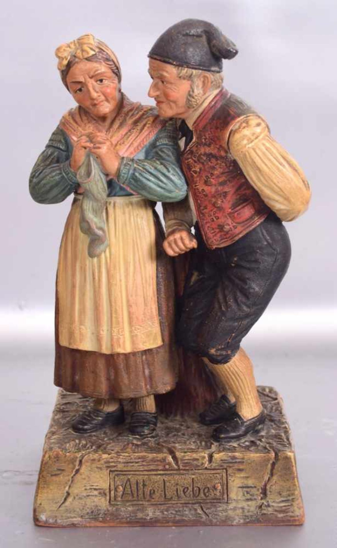 Die alte LiebeBauernpaar, auf rechteckigem Sockel stehend, roter Ton, bunt bemalt, im Boden sign., H