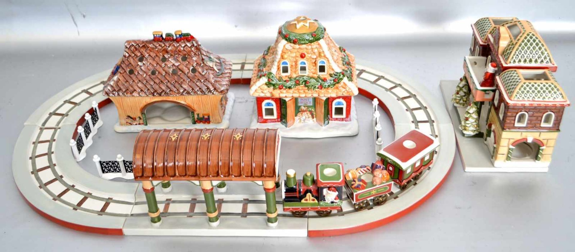 Eisenbahnmit Schienen, drei Häusern, Bahnhof und Zubehör, mit Weihnachtsmotiven verziert, bunt