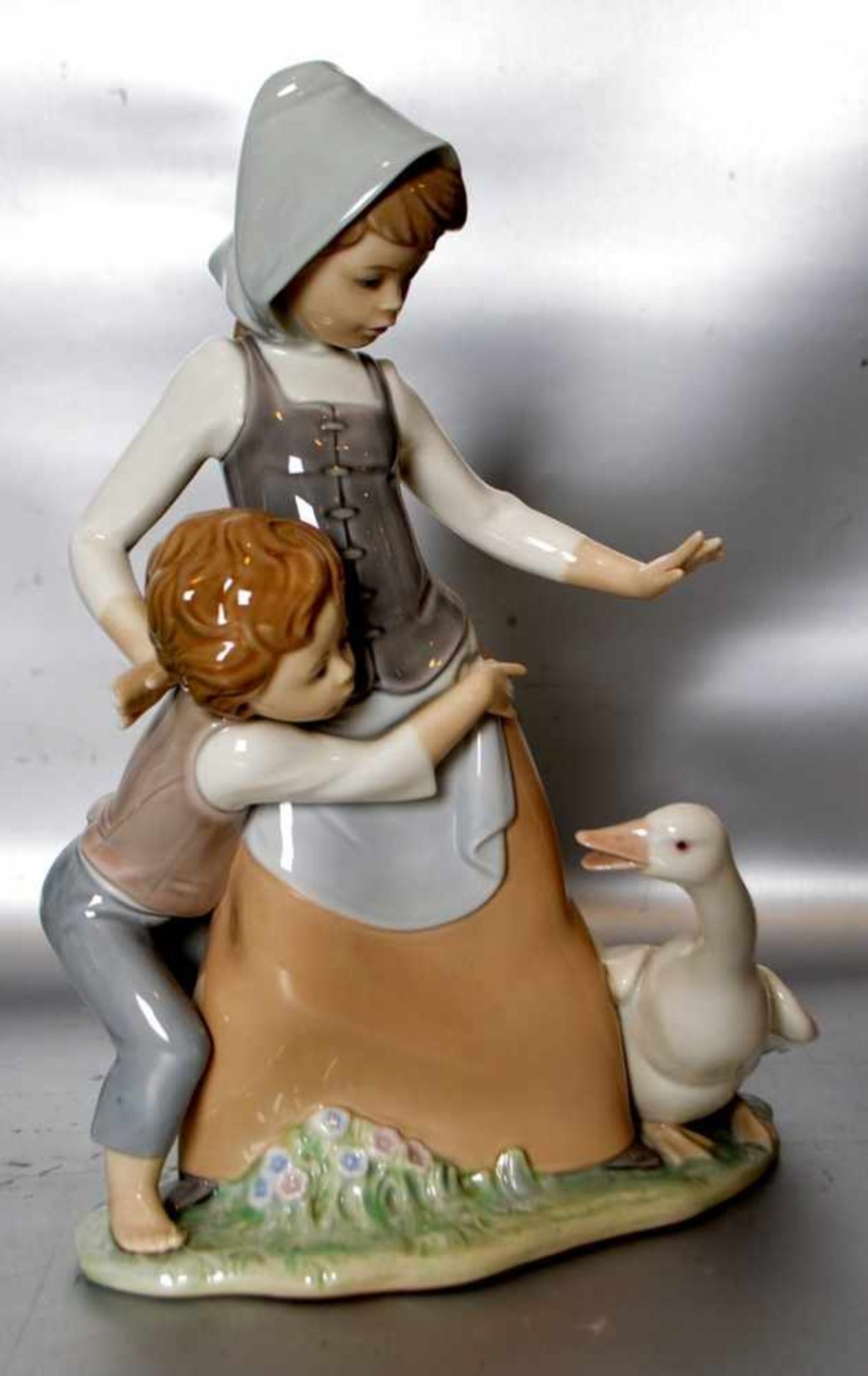 Mädchen mit Gansauf ovalem Sockel stehend, mit kleinem Knaben, bunt bemalt, H 26 cm, FM Lladro