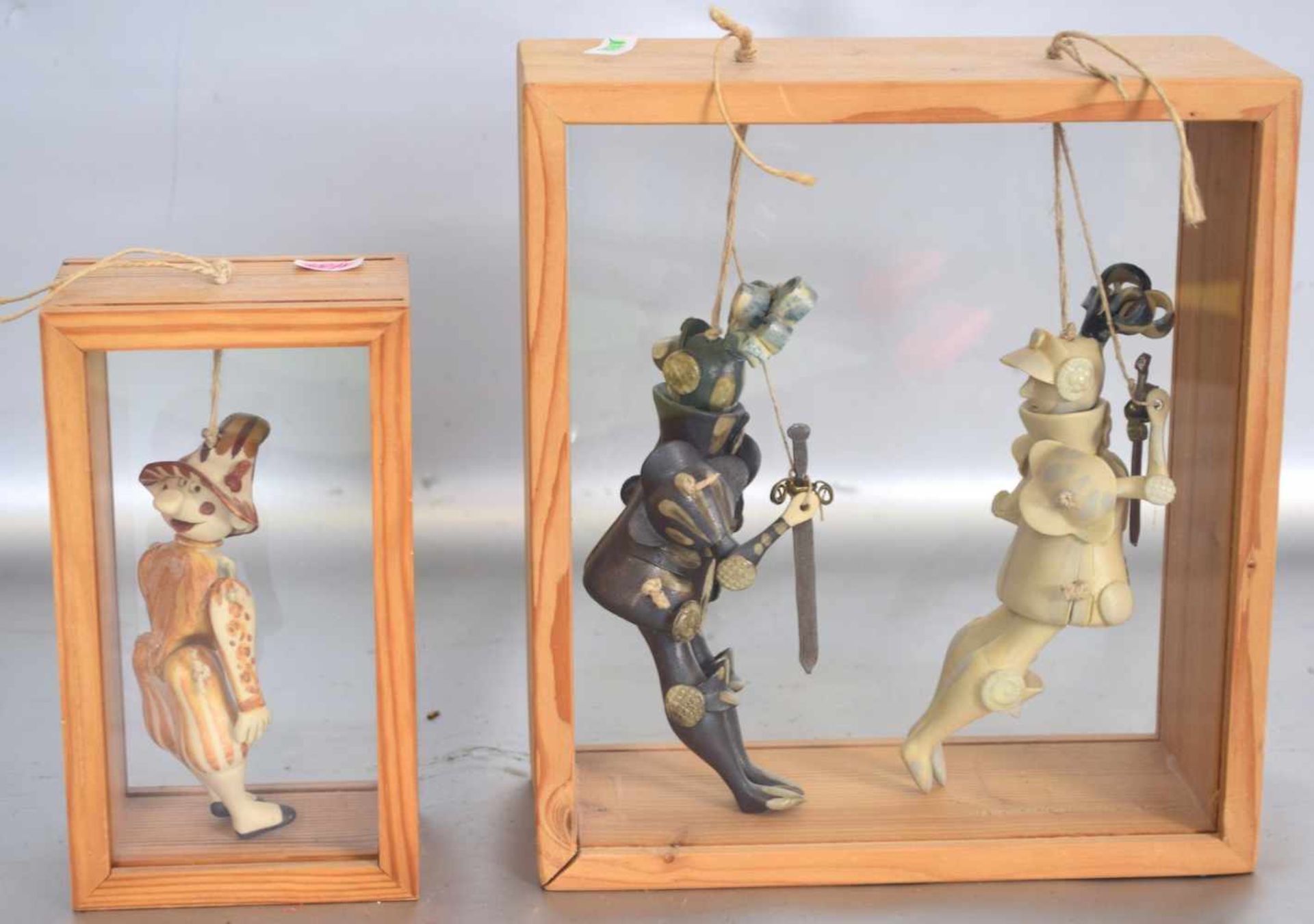 Drei Marionettenim verglasten Holzkasten, Ton, bunt bemalt, H 21 cm bzw. 16 cm