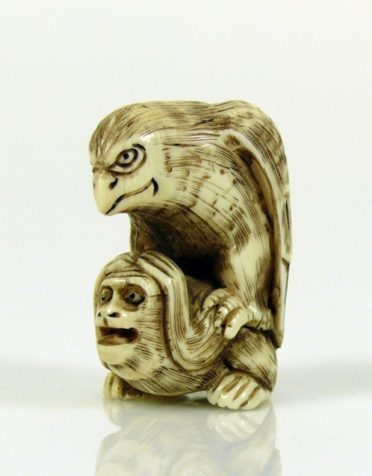 Netsuke (Japan, um 1900)"Adler auf Affe sitzend"; Elfenbein, geritzt und dunkel staffiert;
