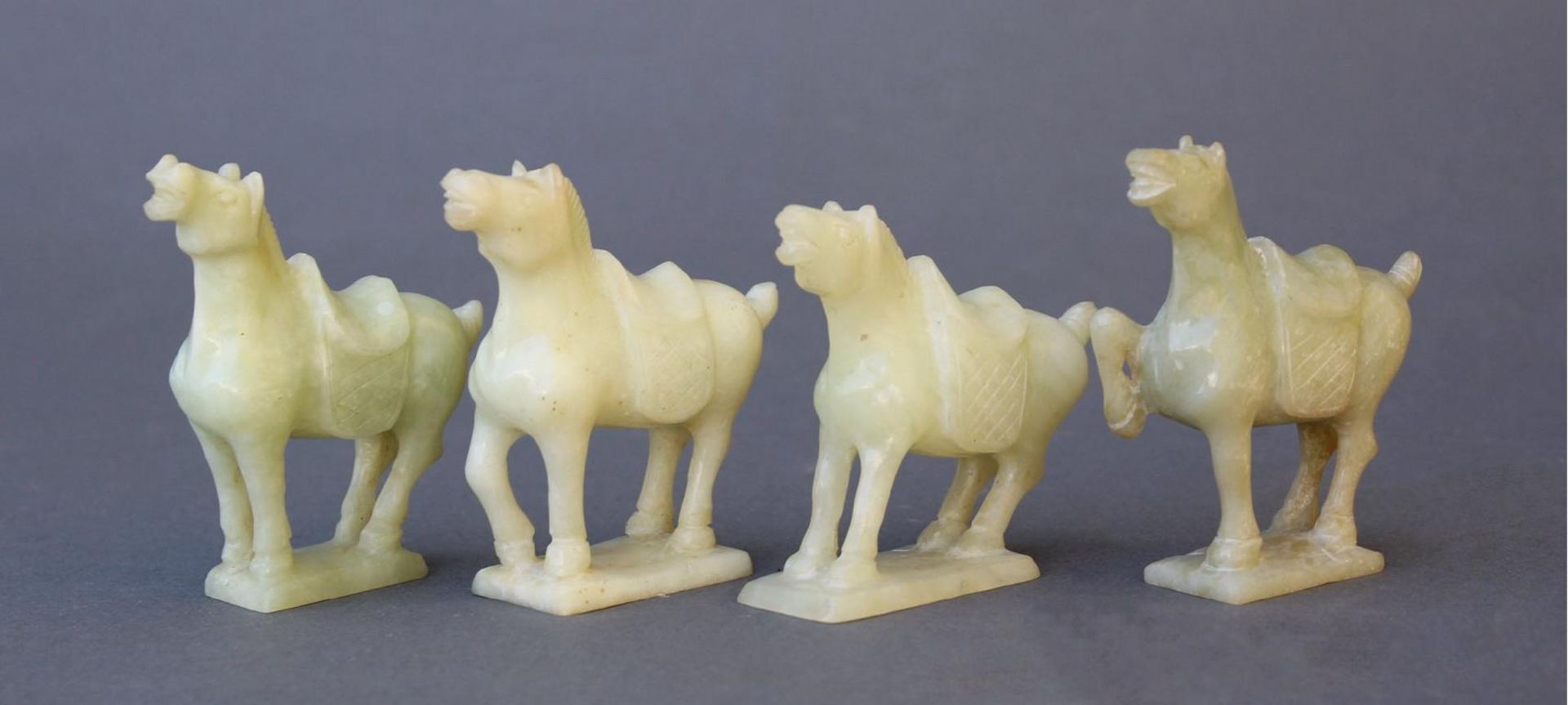 Vier Kleine PferdefigurenChina 20. Jahrhundert, grüne Jade geschnitzt, gesatteltes Pferd auf
