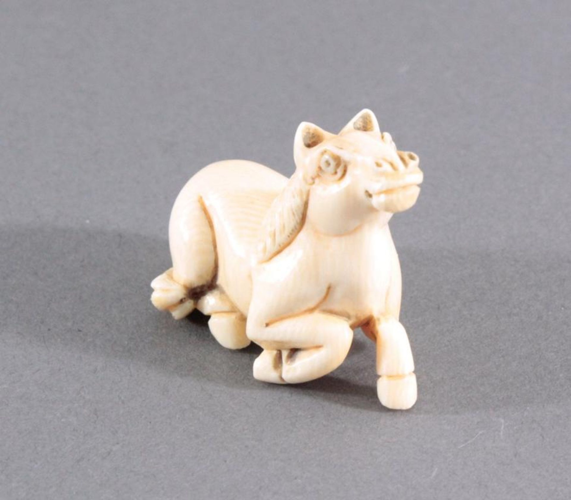 Netsuke, Japan 1. Hälfte 20. Jh., Elfenbein geschnitztVollplastische Schnitzerei, liegendes Pferd,