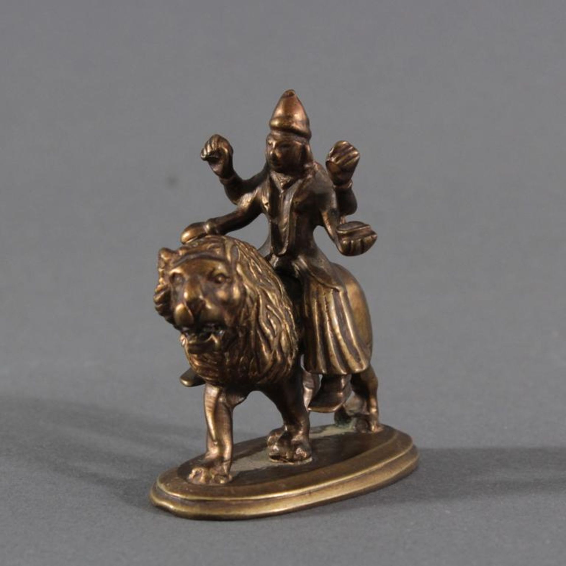 Bronzefigur, "Durga", 19. JahrhundertVierarmige Durga auf einem Löwen. In den Händen verschiedene