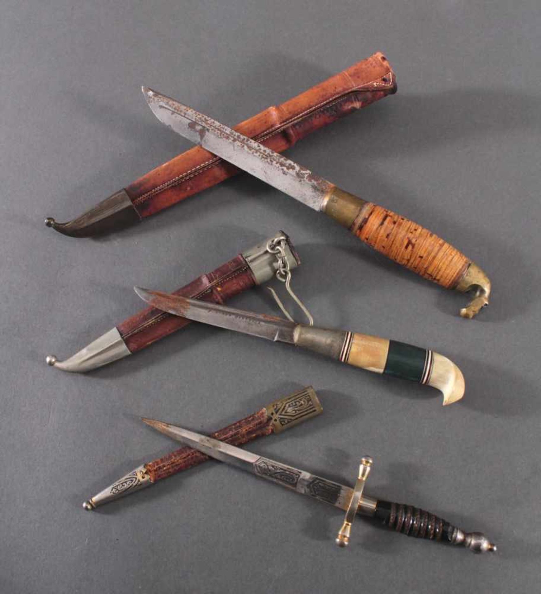 3 Messer2 Messer mit verzierter Klinge, Lederscheide mit Metallaplikationen, Griffe aus Bakelit,
