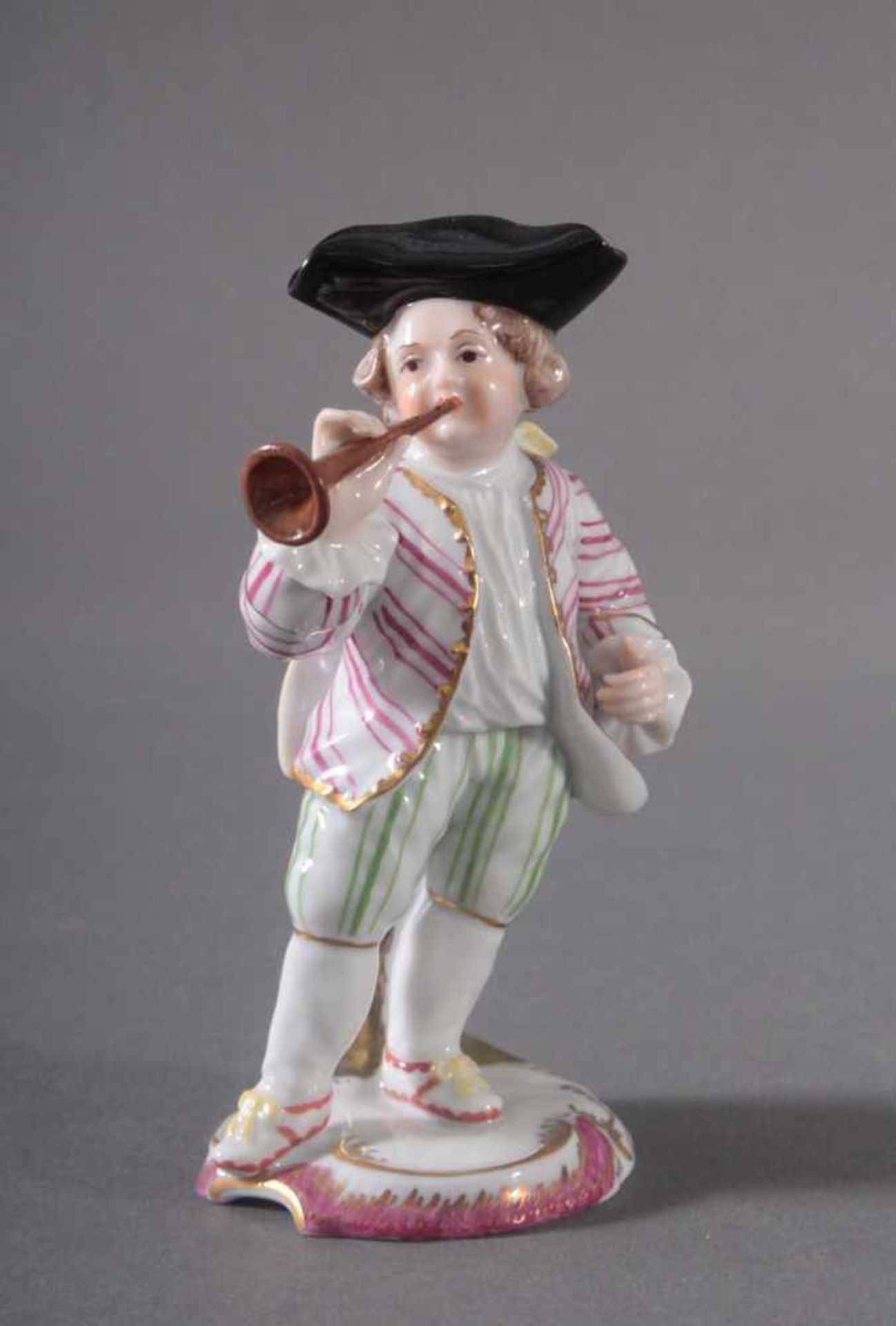 Musiker mit Blasinstrument - HöchstPorzellan, polychrom gefasste Figur auf rocaillierter Plinthe,