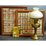 A brass oil lamp; a book, Discovering Oil Lamps; a framed set of cigarette cards,