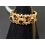 A Modernist gold and garnet five stone dress ring, textured and pierced tapering shank,