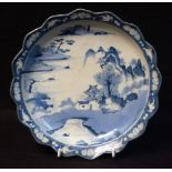A Japanese shaped circular plate, decorated in underglaze blue with pagoda, lake and willow trees,