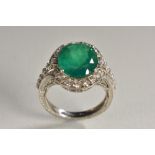 An emerald and diamond oval cluster ring, central oval emerald approx 0.