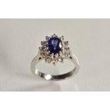 A tanzanite and diamond oval cluster ring, central vibrant tanzanite, measuring approx 8.00mm x 6.