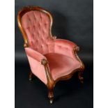 A Victorian mahogany spoon back armchair, carved with a cresting of flowers and foliage,