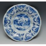 A Delft lobed circular dish, decorated in underglaze blue with stylised figure and foliage,