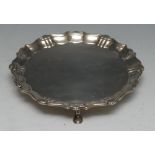 A George II silver shaped circular card waiter, fluted shell and S-scroll border, hoof feet,