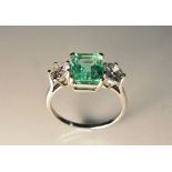 An emerald and diamond trilogy ring, rectangular table cut emerald approx 2.