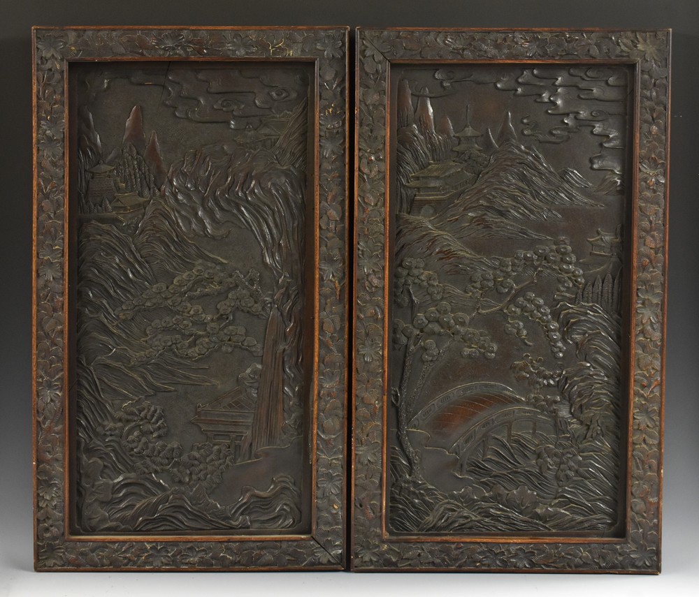 A pair of Chinese hardwood rectangular panels, each carved with a temple in a monumental landscape,