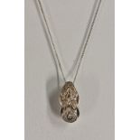 A diamond accented white metal pendant, stamped 14k, suspended from a 9ct whit gold fine link chain,