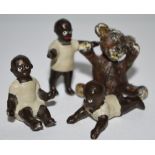 A set of three cold painted figures, of negro children; another,