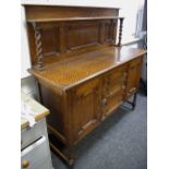 An oak sideboard, shelf and barley twist supports to panelled gallery, oversailing top,