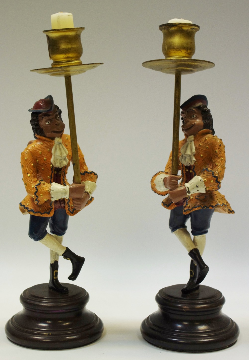 A pair of novelty cold painted metal candlesticks of a monkey in 18th century dress,