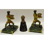 A pair of novelty cold painted candlesticks in the form of monkeys raised on a cushion base;