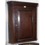 An oak wall mounted corner cupboard stepped cornice canted front, fielded panel door,
