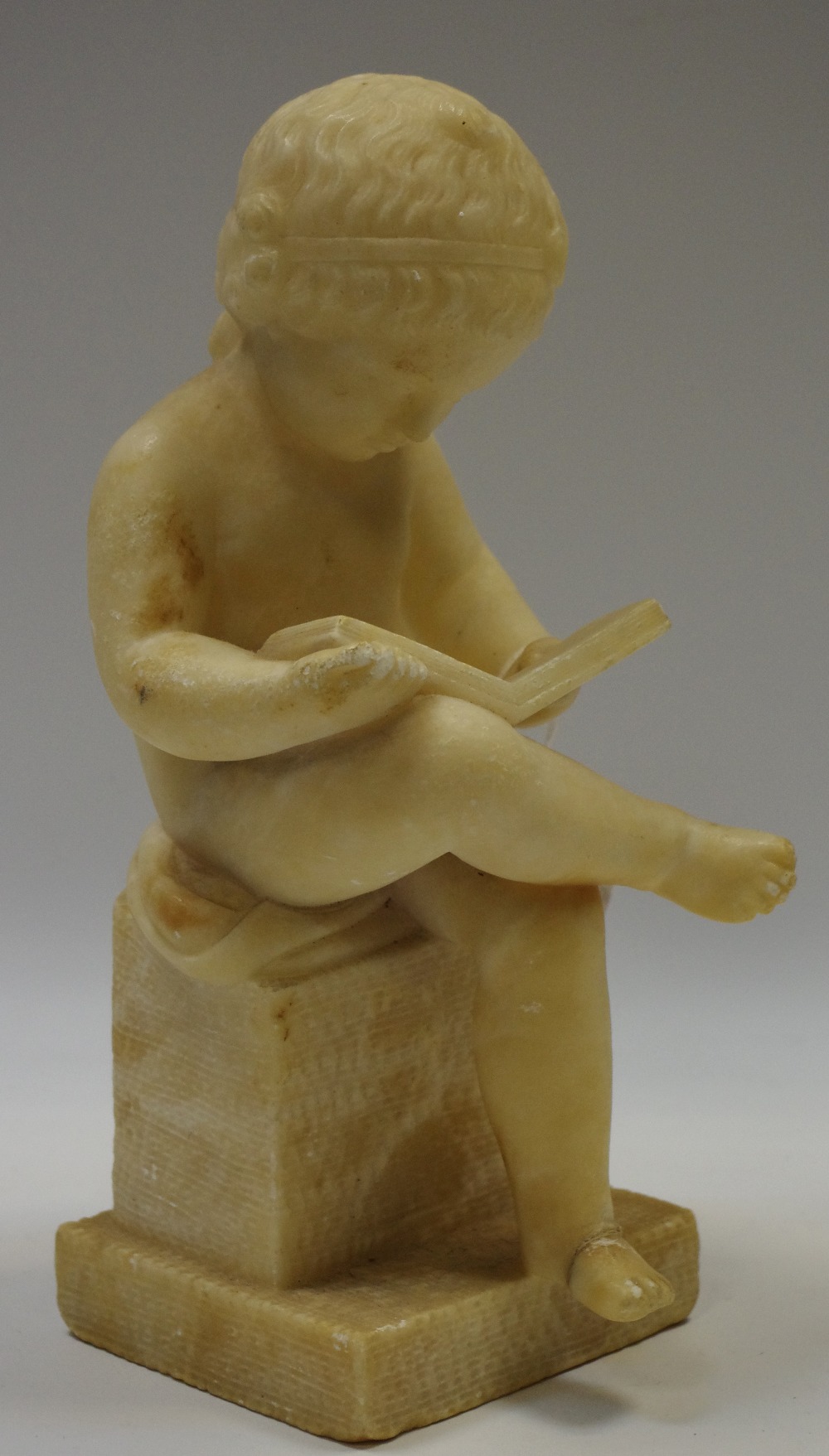 French School (19th century), an alabaster figure, of a putto reading,