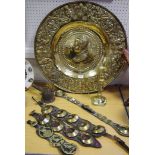 A large embossed brass charger; horse brasses; an ejector candlestick;